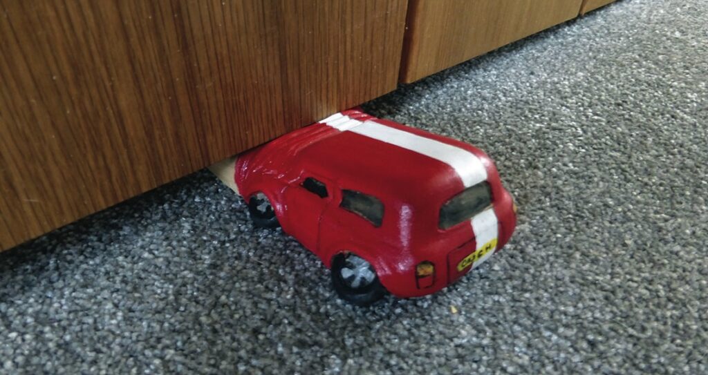 Novelty car doorstop in use on carpet