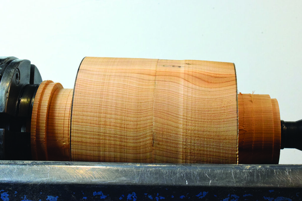 Woodturning: cylindrical wood piece on lathe machine.