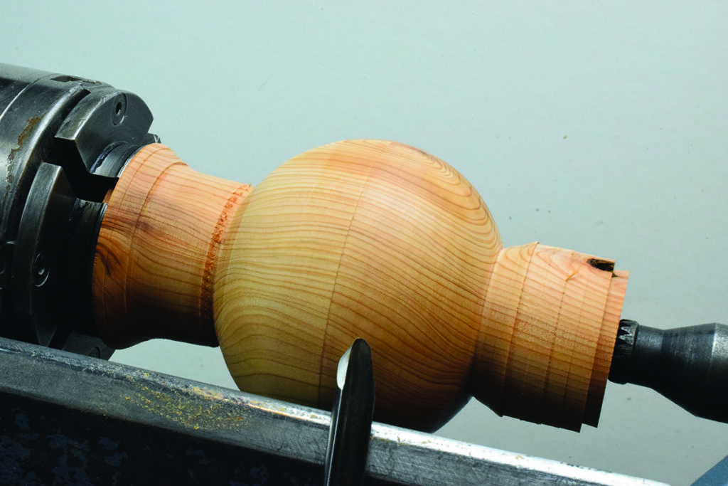 Woodturning on lathe with chisel tool.