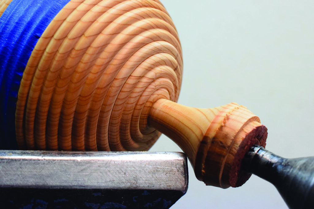 Woodturning bowl on lathe with intricate design.