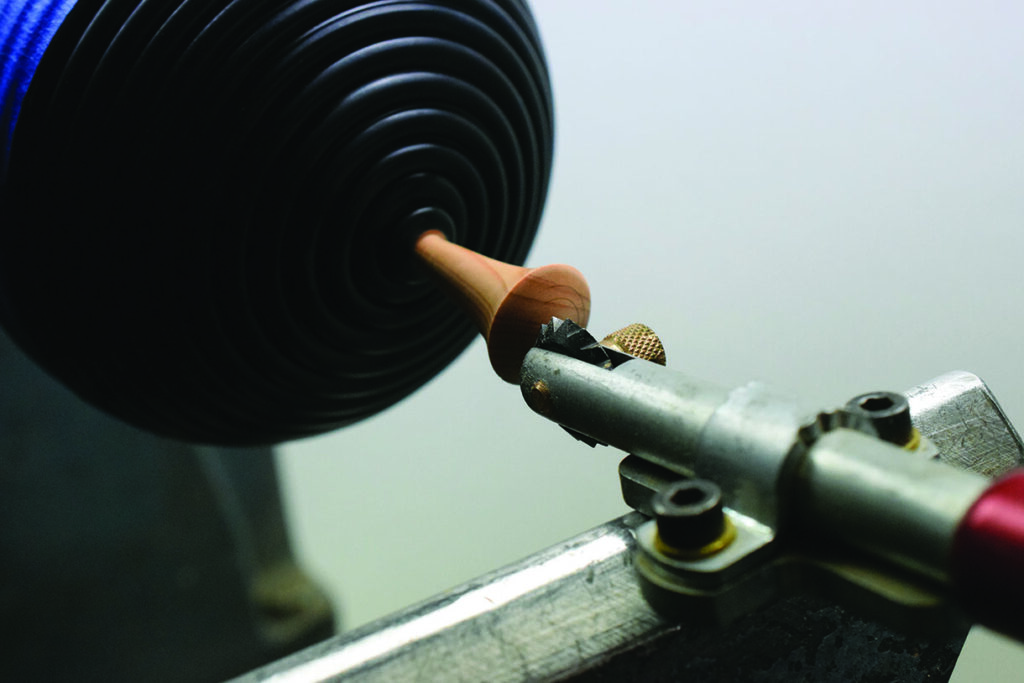 Woodturning tool carving a spinning wooden piece.