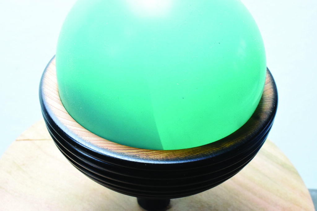 Green glass sphere on wooden base.