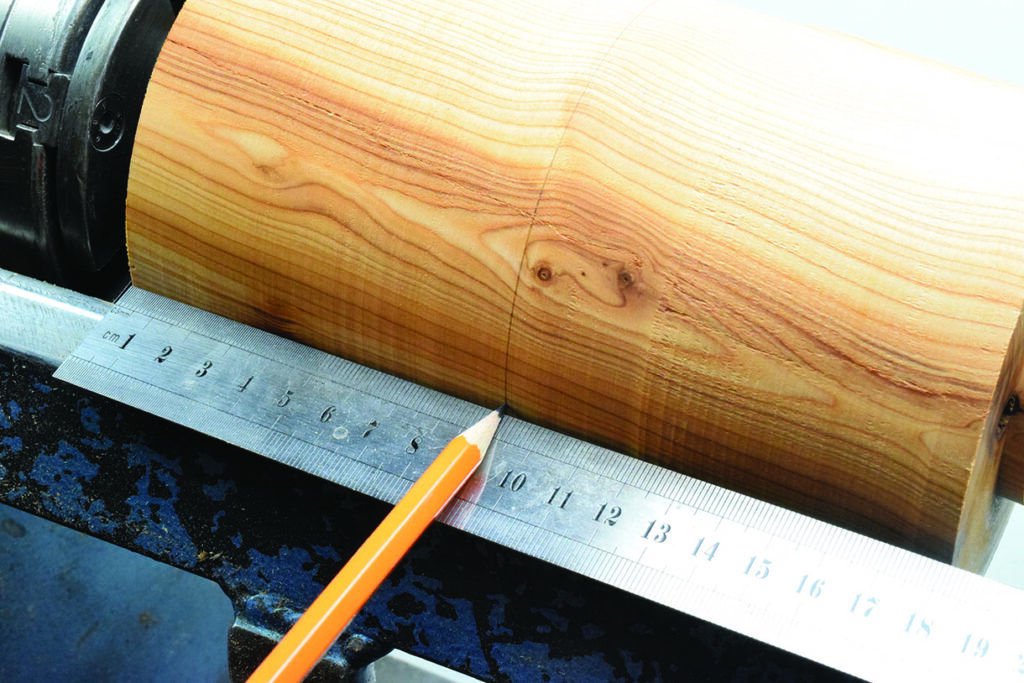 Pencil marking wood with ruler for measurement.