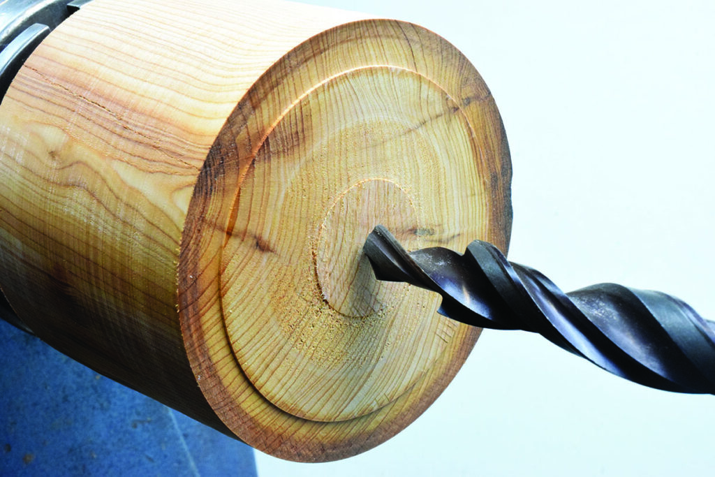 Drilling into wooden log with a drill bit.