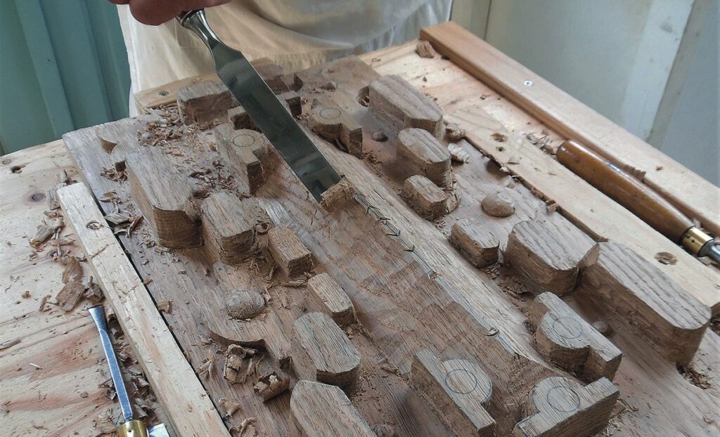 Hand carving wood with chisel on workbench.