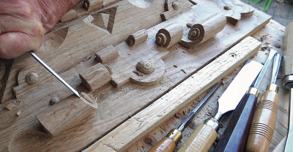 Hand carving intricate wood design with tools