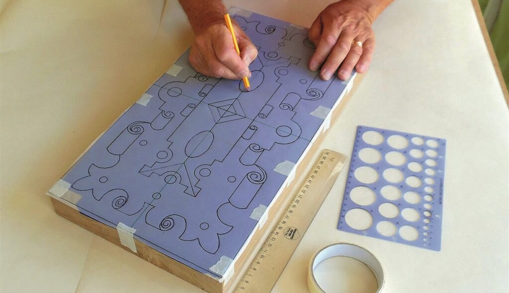 Person drawing geometric shapes on paper with stencils