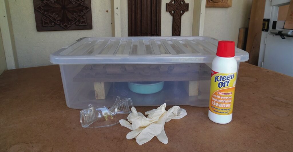 Plastic container with gloves, goggles, cleaner in garage.