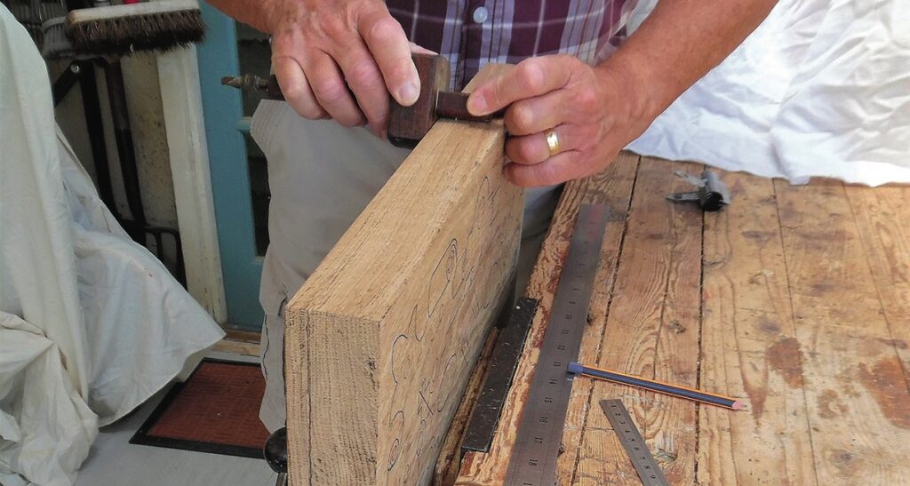 Carpenter using plane on wooden plank.