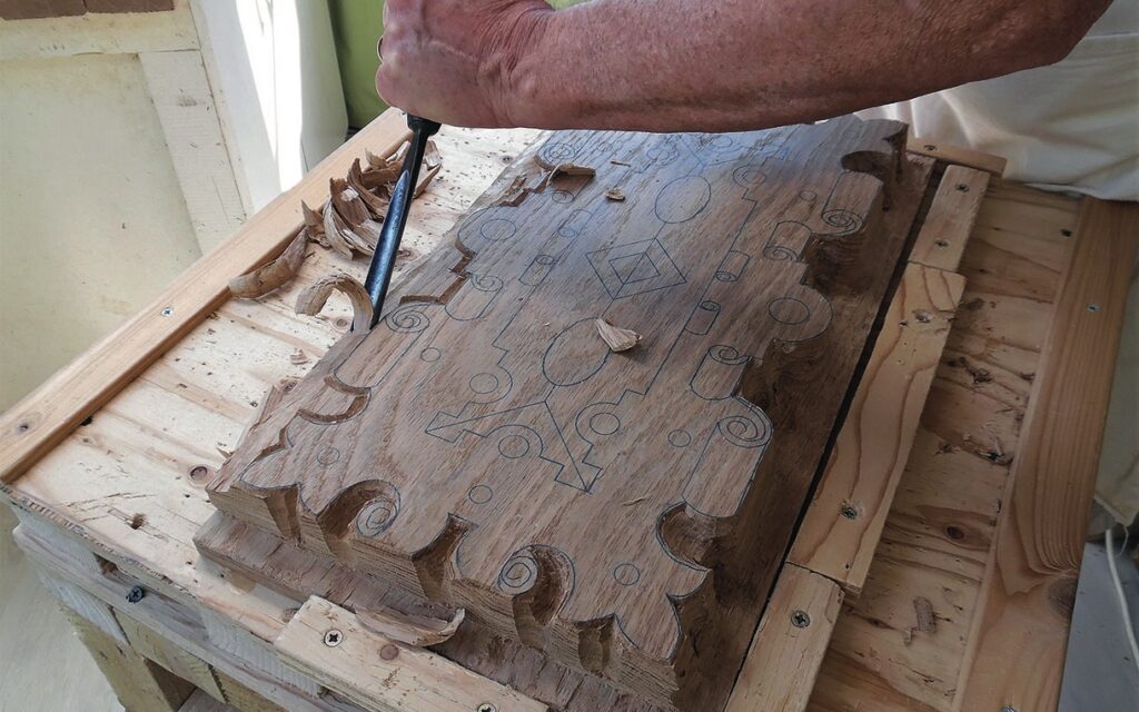 Woodworker carving intricate designs on wooden panel.