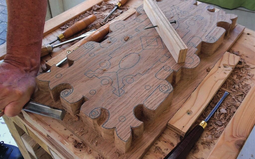 Artisan carving decorative wood pattern with chisel.