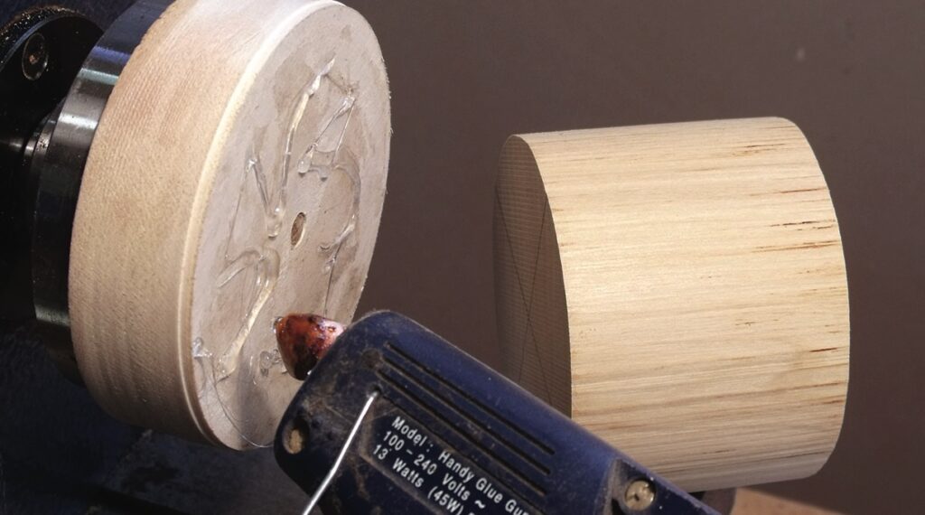 Glue gun aligning wooden discs for crafting.