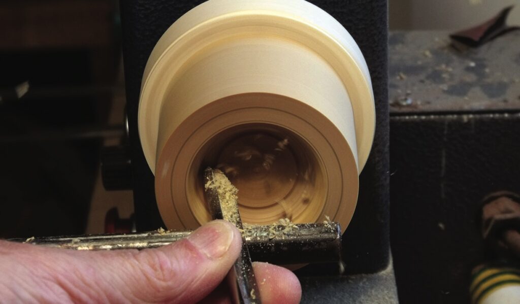 Woodturning on a lathe with chisel tool.