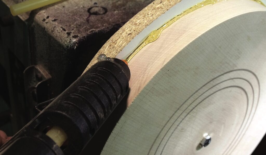 Applying glue to wood with hot glue gun.