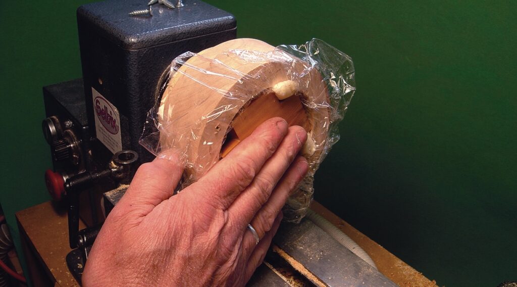 Hand using lathe to shape wooden piece