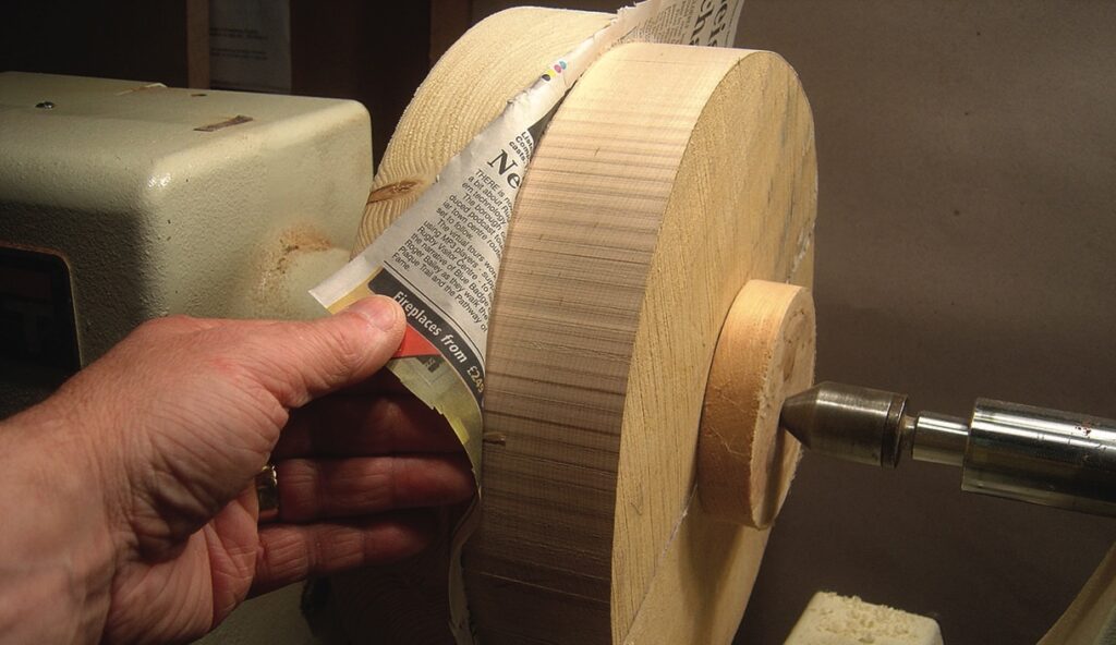 Person using newspaper for woodturning on lathe