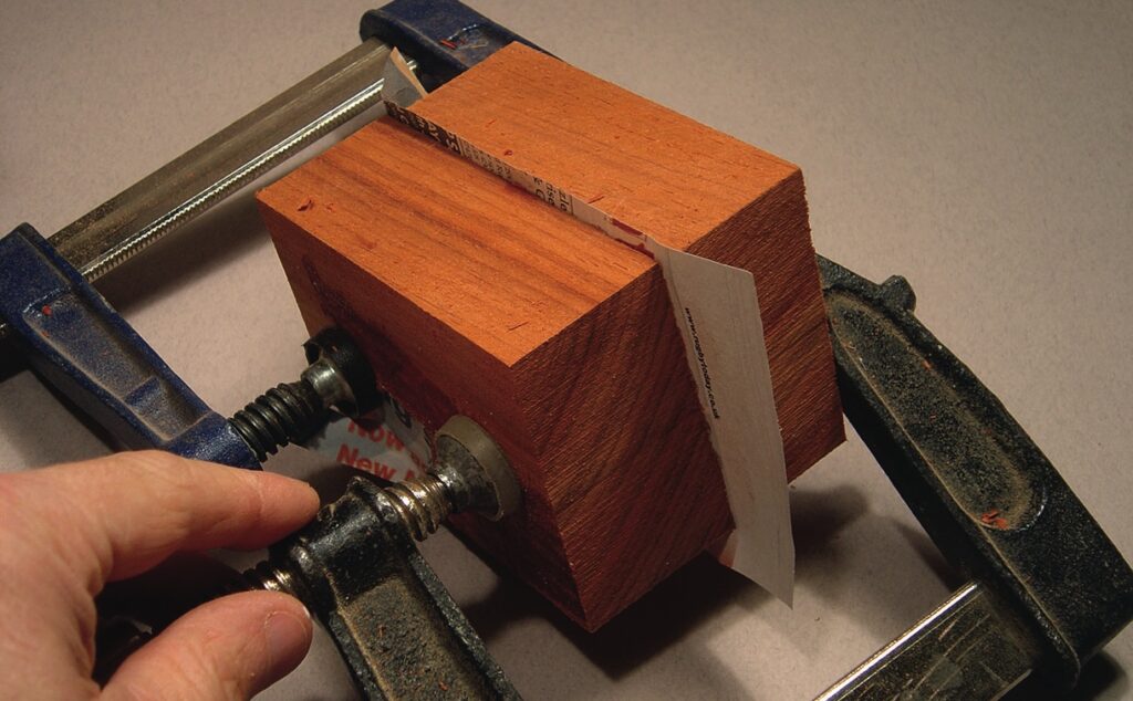 Wood shim in a clamp for woodworking project.