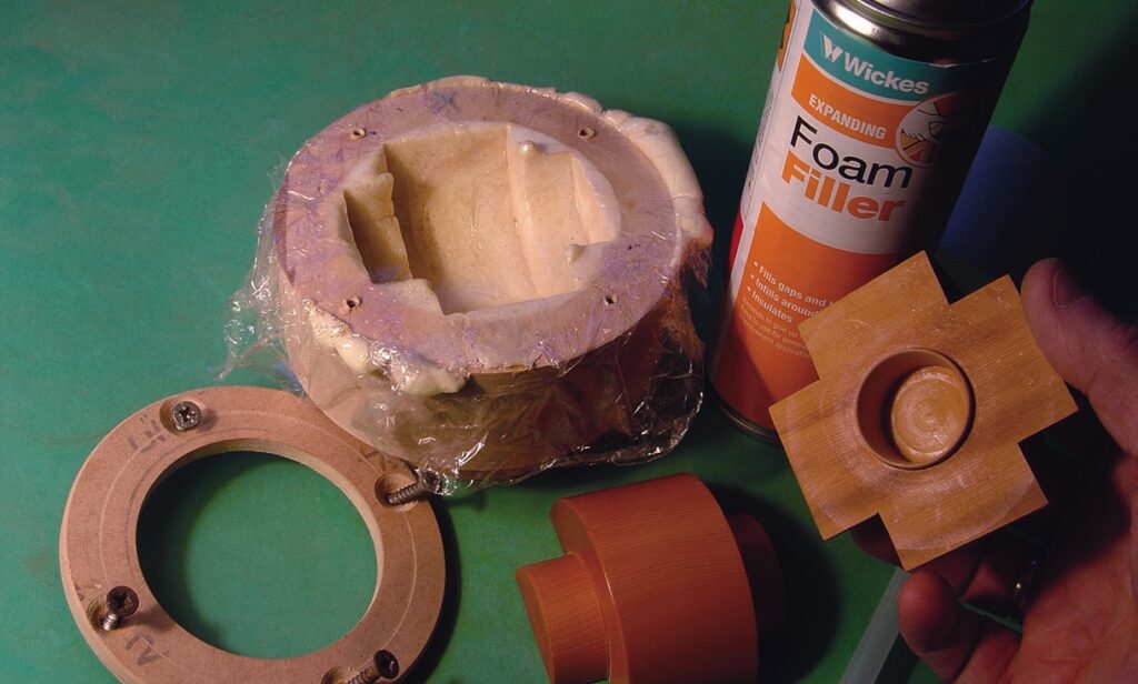 Foam filler and wooden mould components on green surface.