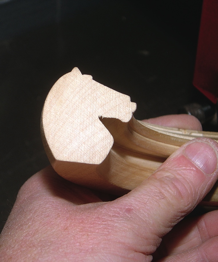 Hand holds carved wooden horse-head violin detail