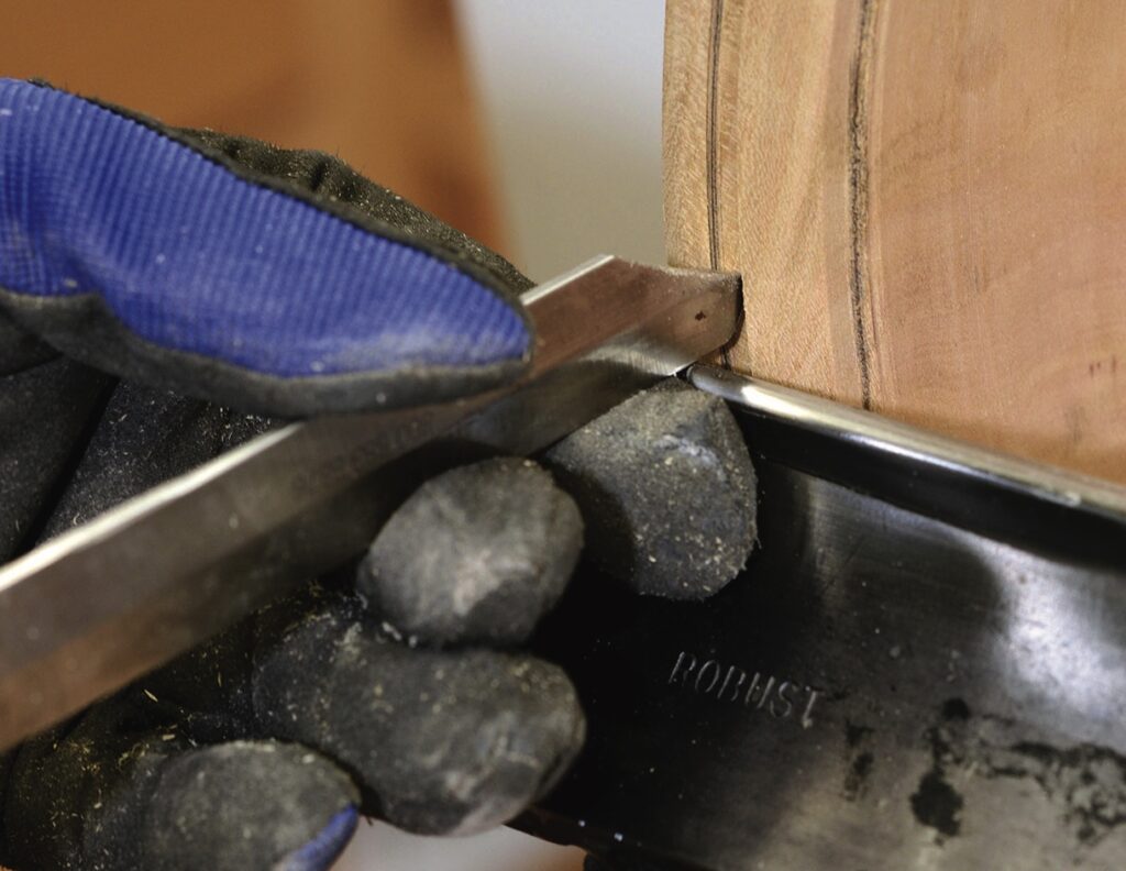 Person woodworking with chisel and lathe tool.