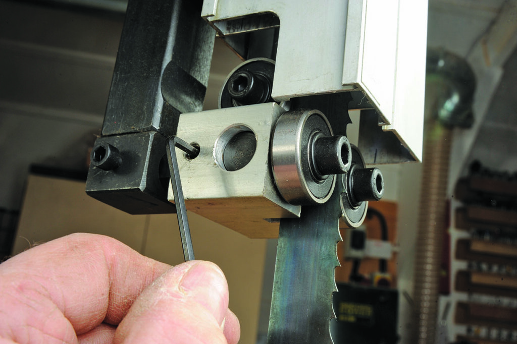 Adjusting bandsaw guide with Allen key.