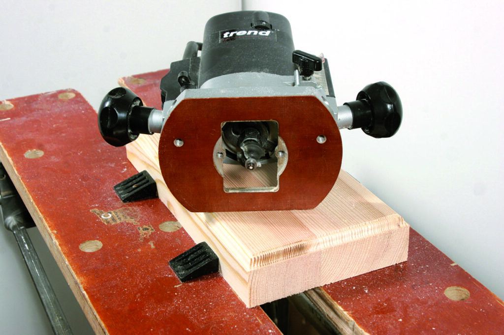 Wood router on workbench cutting timber piece.