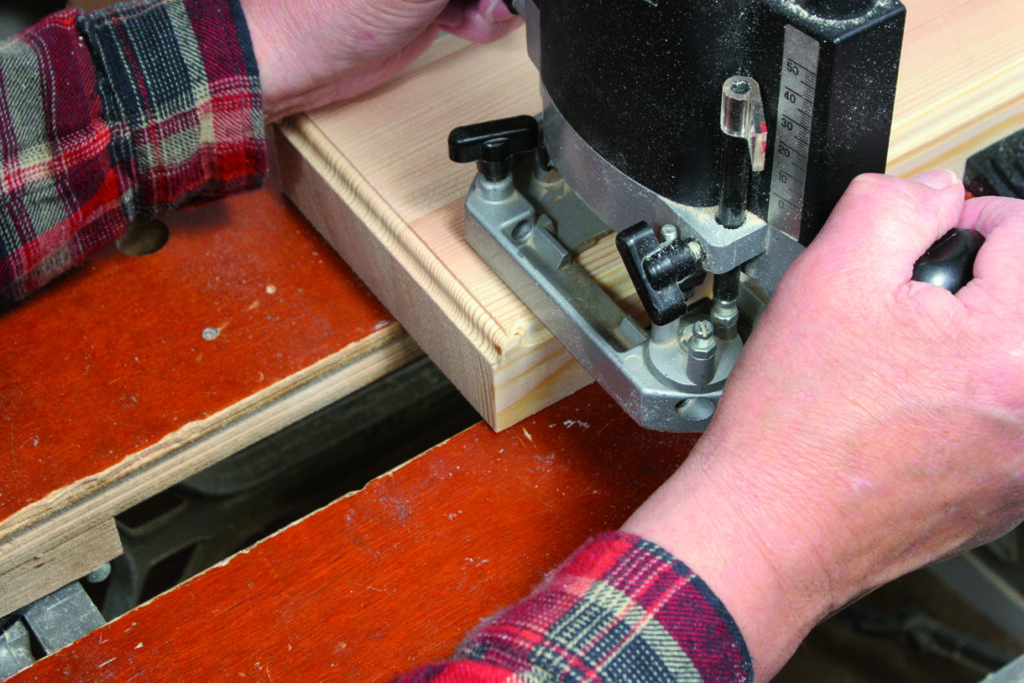 Person using router tool on wooden board.