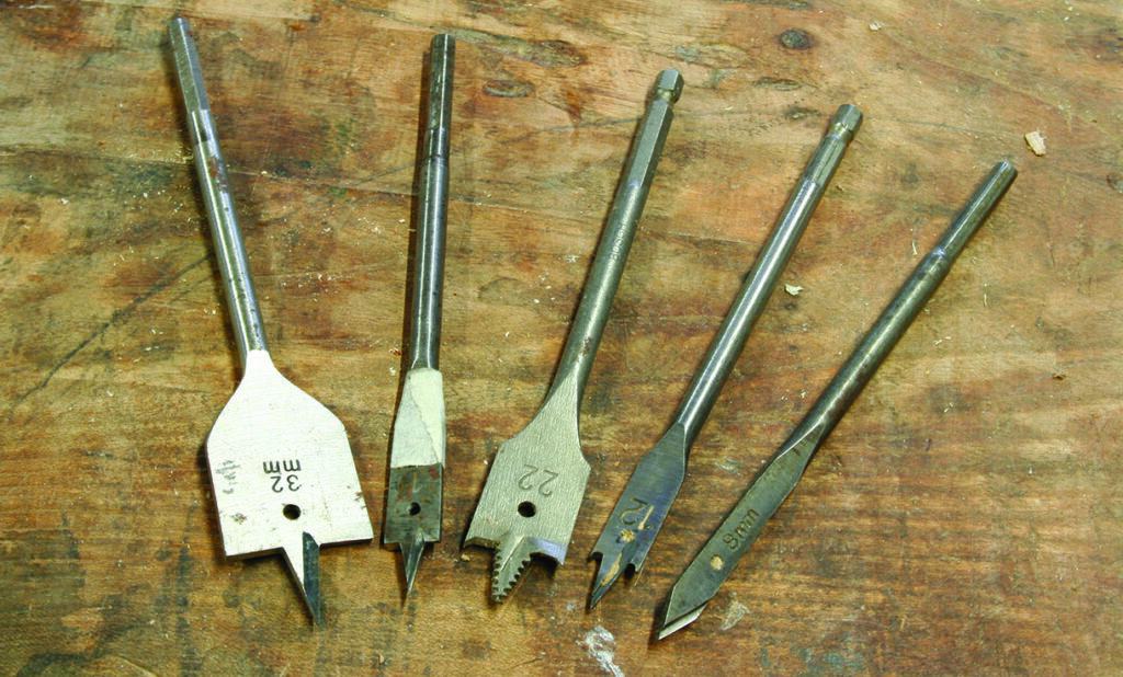 Assorted spade drill bits on wooden surface.
