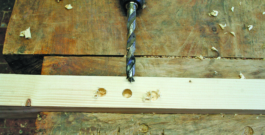 Drilling holes in wood on workbench