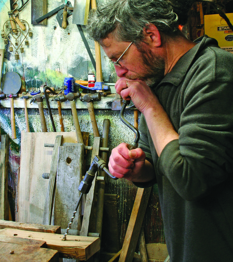 Man using hand drill in workshop.