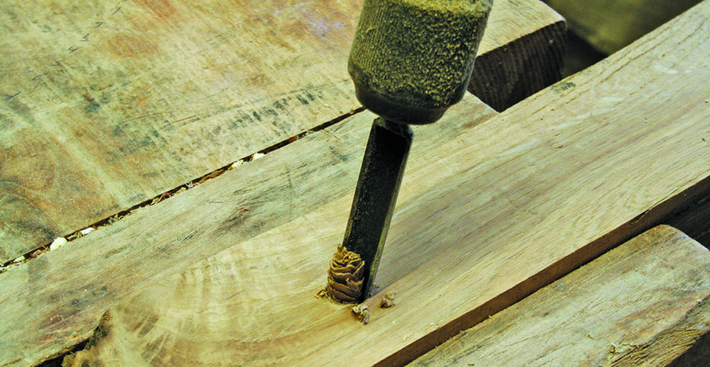 Chisel carving into a wooden plank.