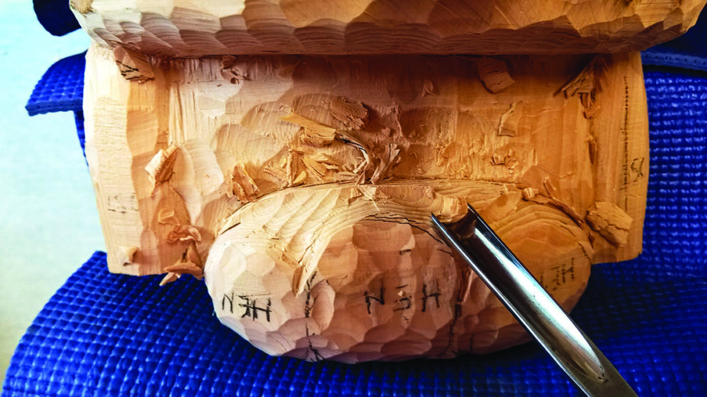 Wood carving in progress with chisel tool.