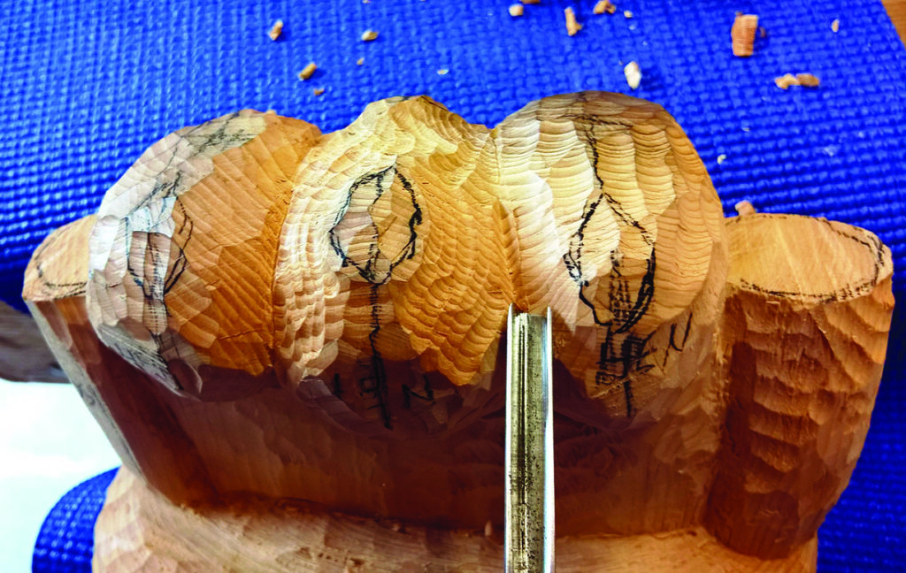 Wood carving in progress on blue mat.