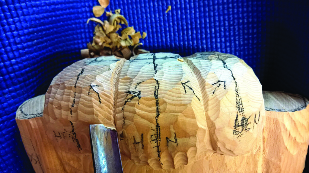 Wood carving with chisel and detailed markings.