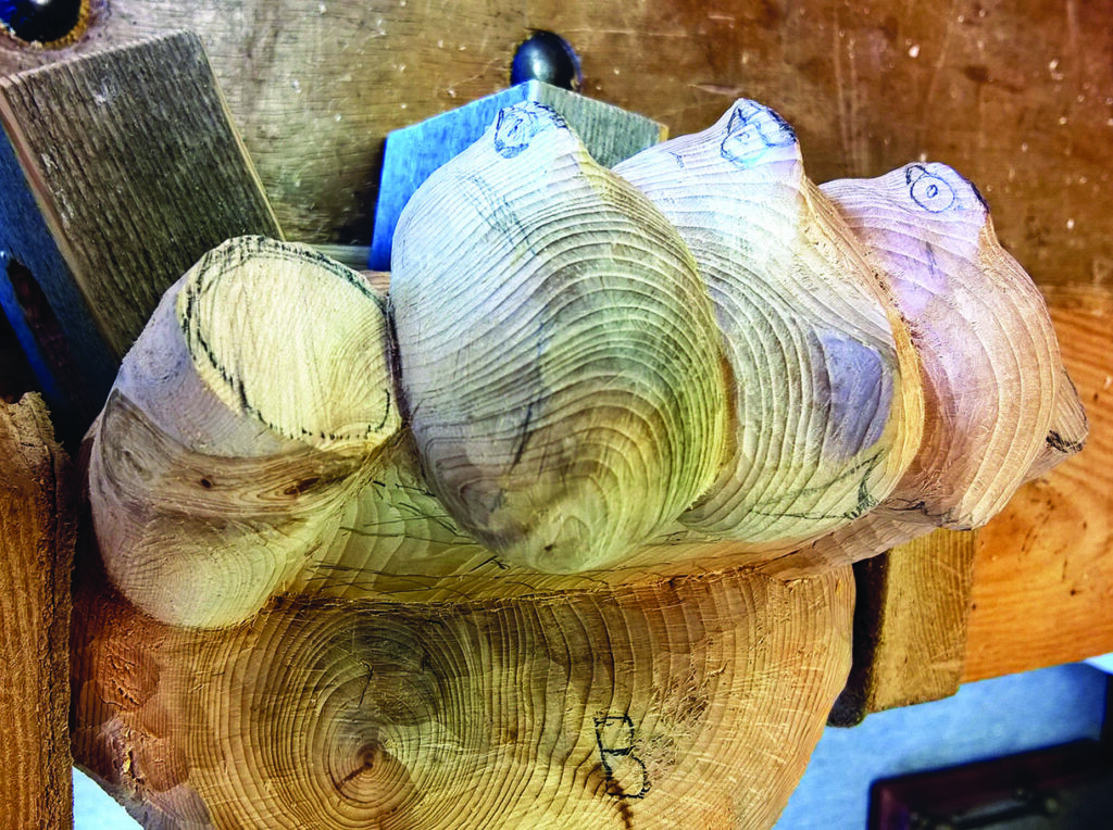 Wooden sculpture with twisting shapes on workbench.