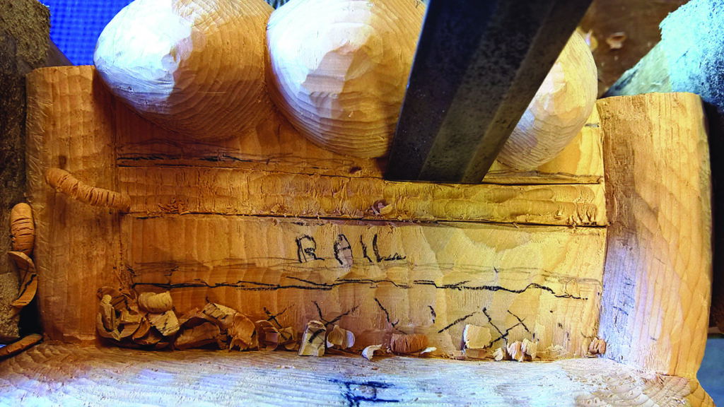 Carved wooden piece with circular shapes and tool