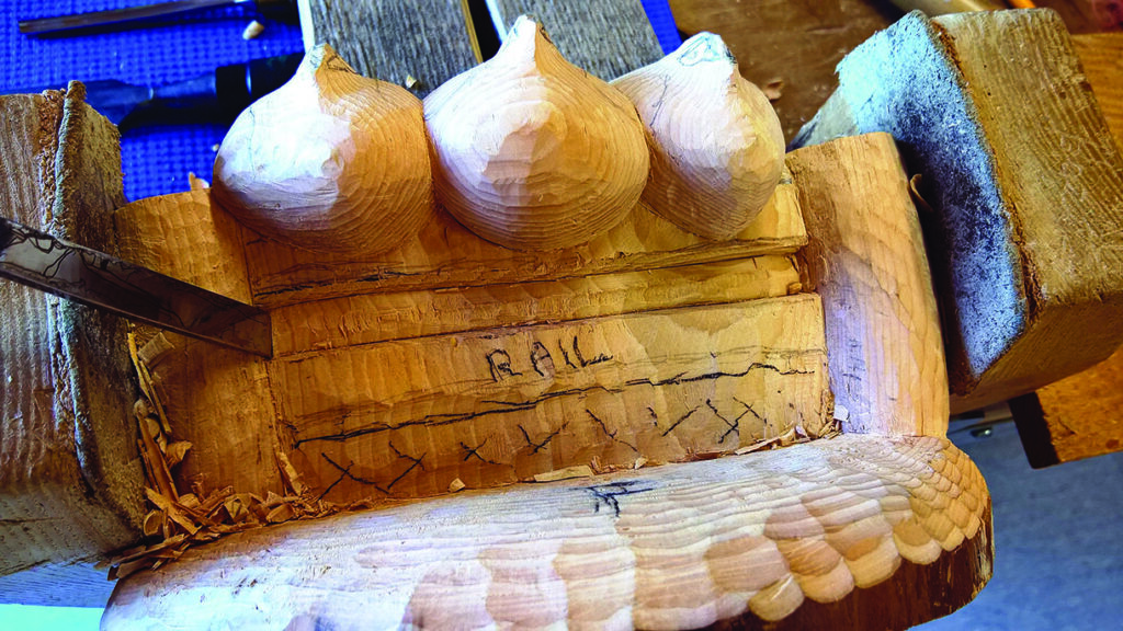 Wood carving of three acorns in progress