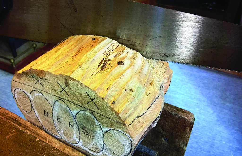 Saw cutting through marked wooden block.