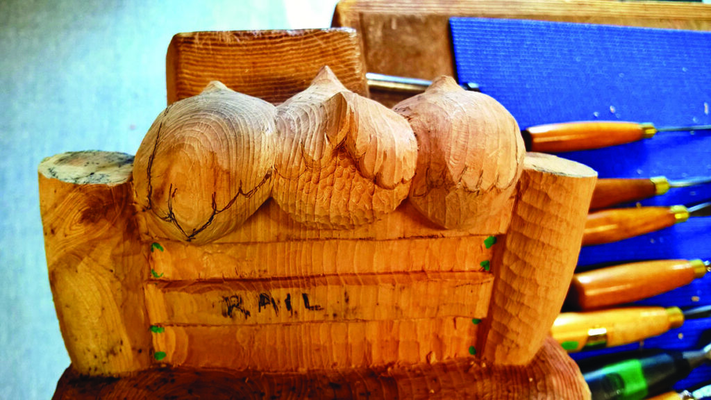 Wooden owl sculpture with carving tools nearby.