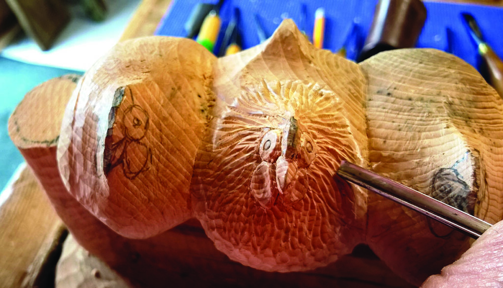 Wood carving of owl in progress on workbench.