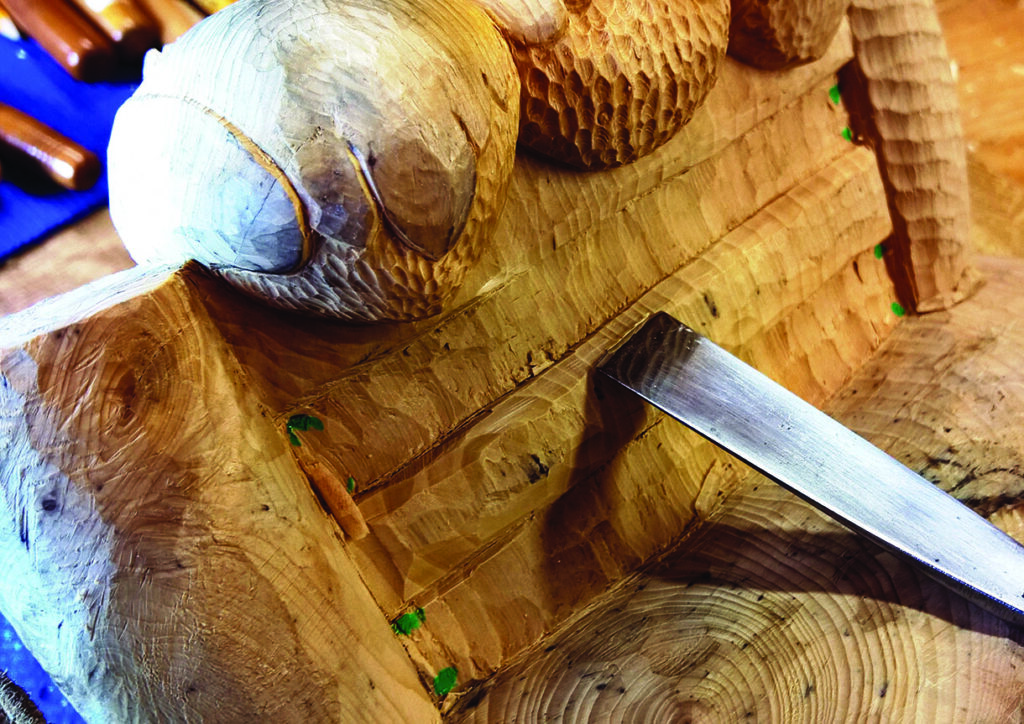 Wood carving in progress with chisel tool.