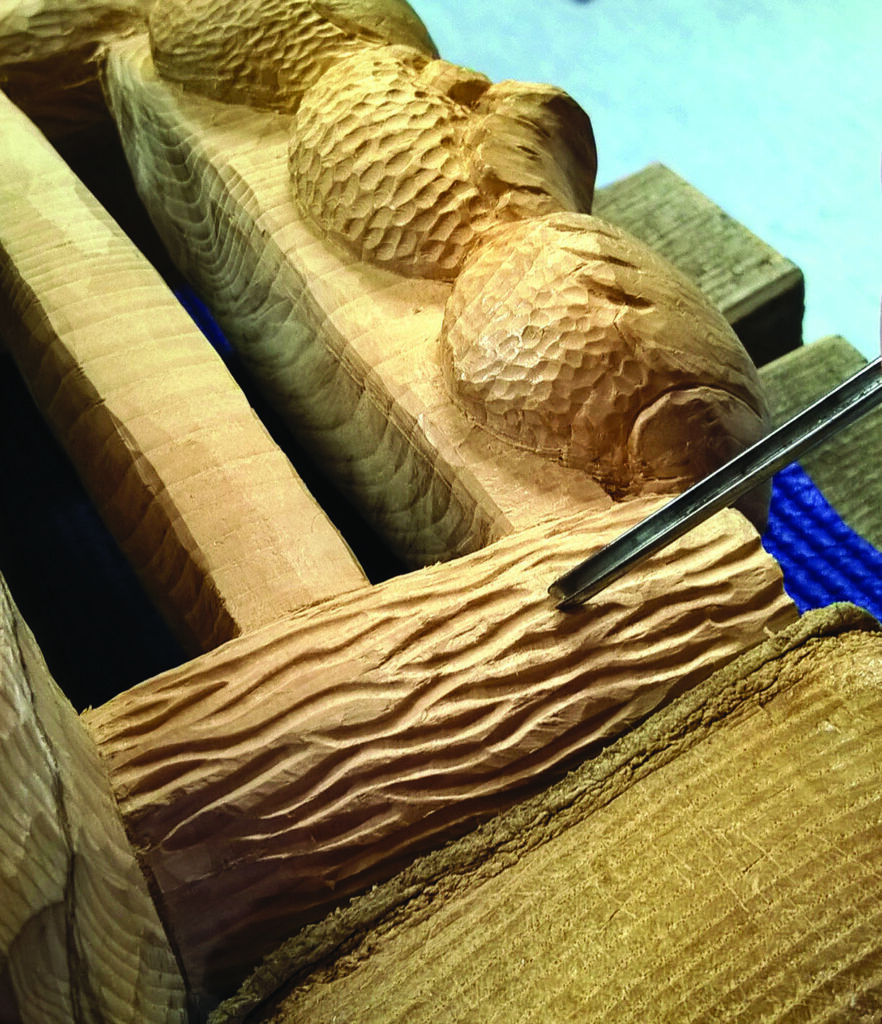 Close-up of intricate wood carving with chisel tool.