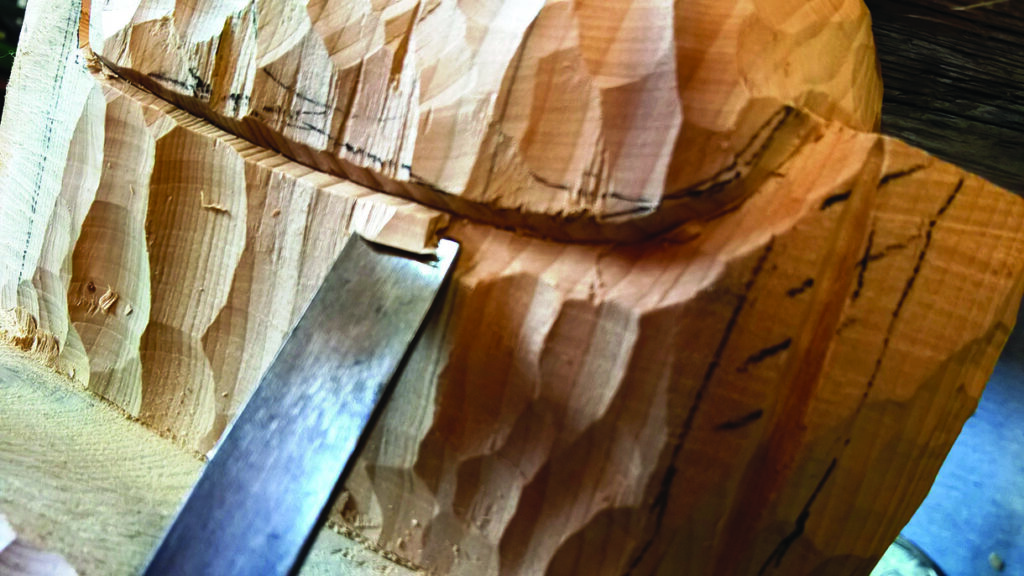 Wood carving with chisel in close-up view.
