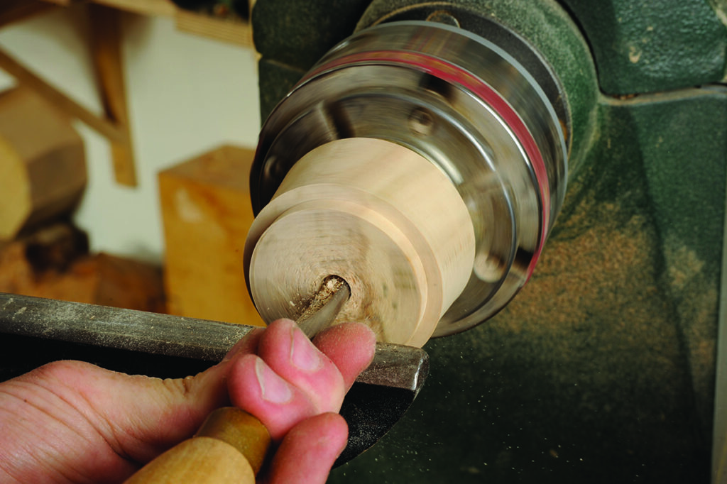 Hand carving wood on a lathe machine.