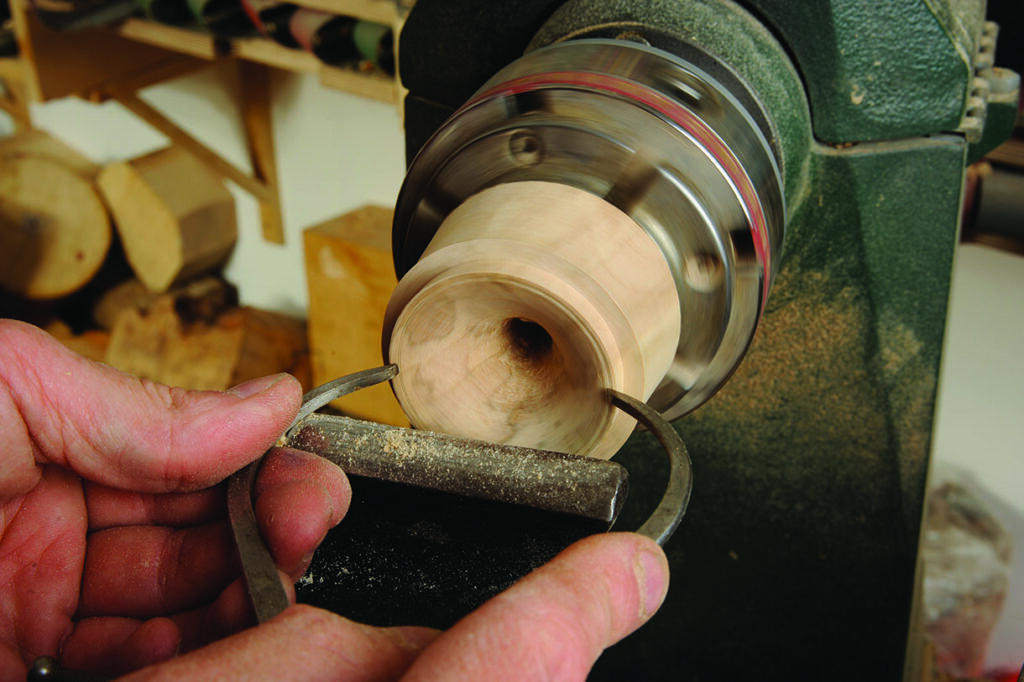 Woodturning on a lathe in workshop.