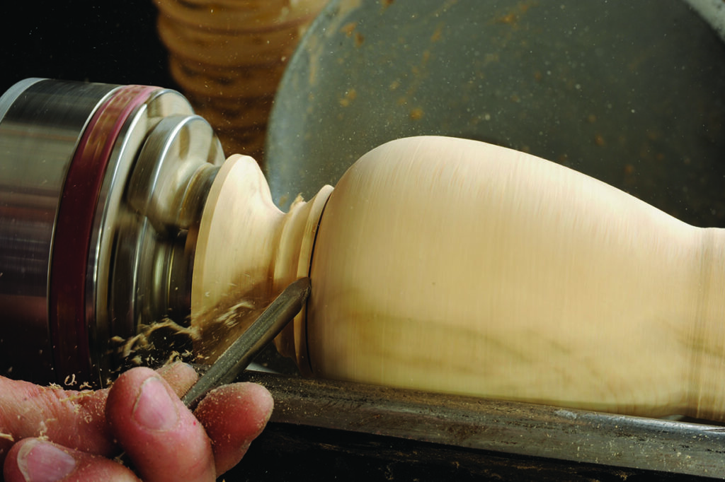 Woodturning with lathe and chisel creating vase