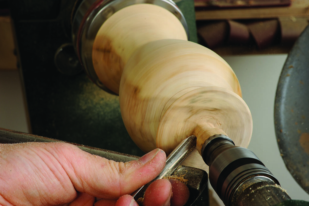 Craftsman turning wood on a lathe machine