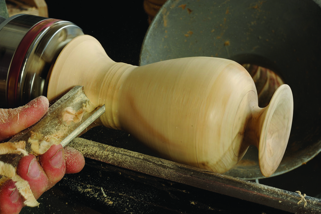 Woodturning bowl on a lathe in workshop.