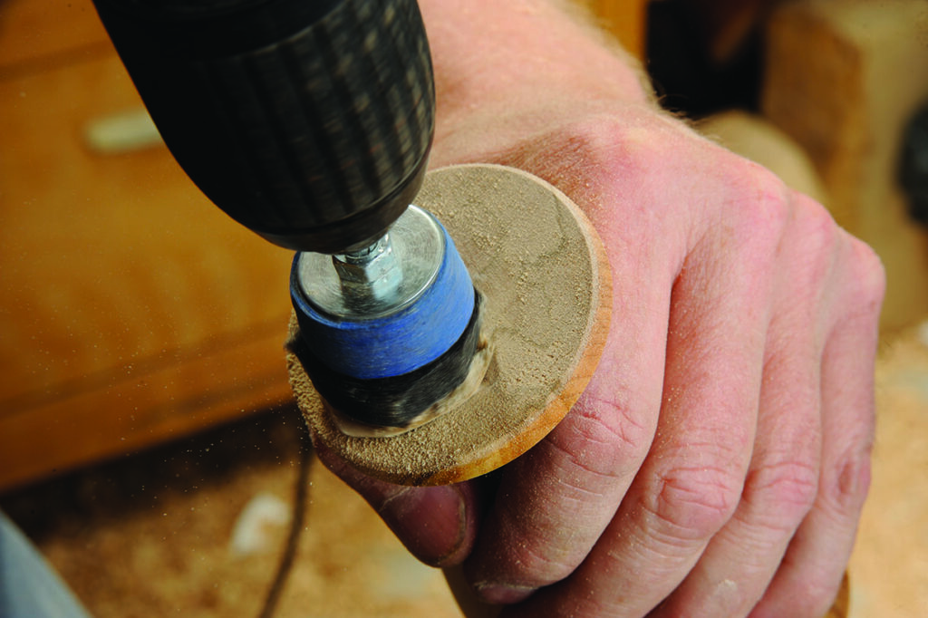 Sanding wood with handheld electric tool.