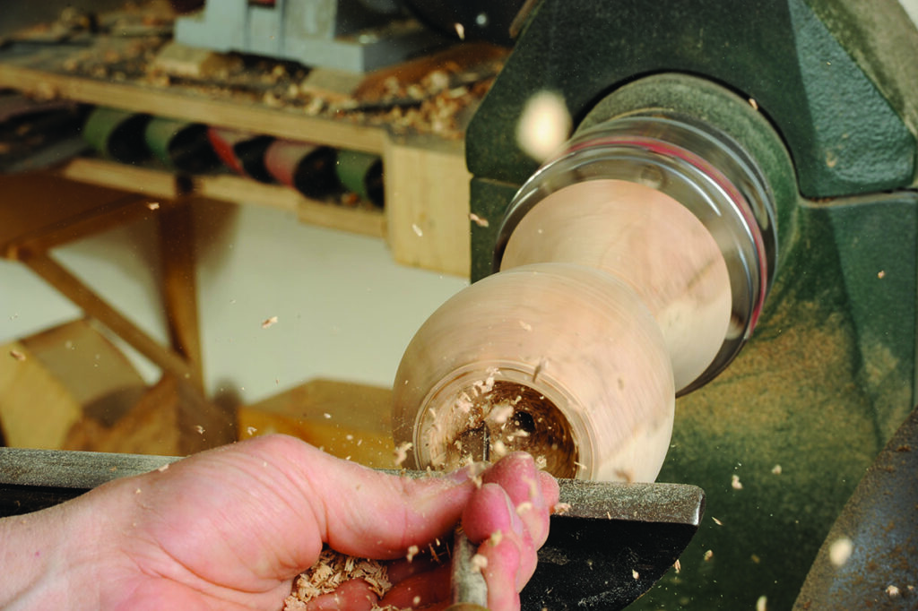 Woodturning on a lathe, creating wooden object.